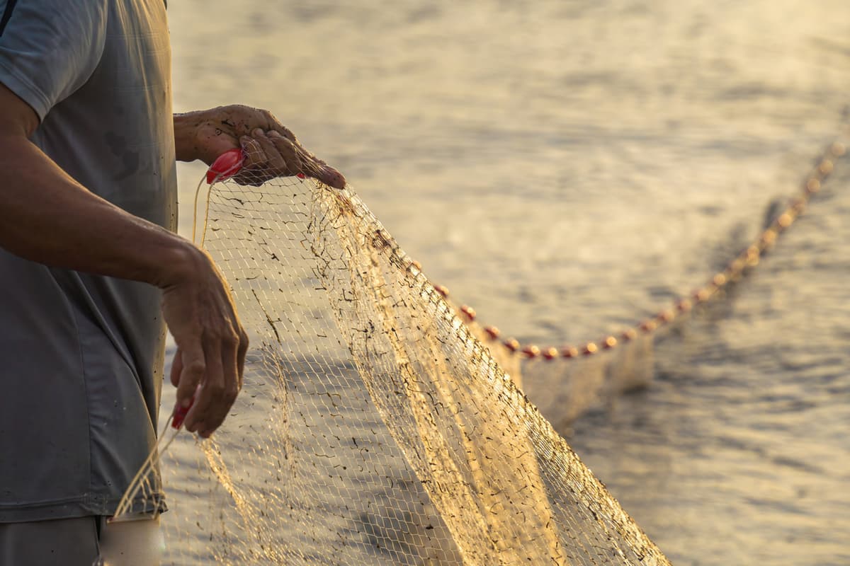 Pescador lançando sua rede ao nascer do sol ou ao pôr do sol